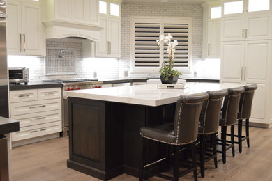 Klassisk inredning av ett mellanstort vit vitt l-kök, med en rustik diskho, skåp i shakerstil, vita skåp, marmorbänkskiva, vitt stänkskydd, stänkskydd i tunnelbanekakel, rostfria vitvaror, ljust trägolv, en köksö och brunt golv