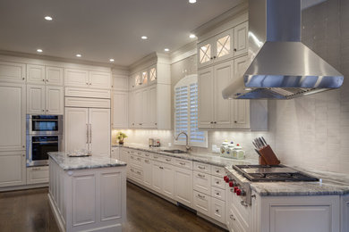 Enclosed kitchen - mid-sized traditional l-shaped dark wood floor enclosed kitchen idea in Houston with an undermount sink, raised-panel cabinets, beige cabinets, quartzite countertops, beige backsplash, porcelain backsplash, paneled appliances and an island