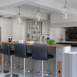 Expansive classic l-shaped open plan kitchen in Surrey with shaker cabinets, grey cabinets, quartz worktops, metallic splashback, mirror splashback, stainless steel appliances, porcelain flooring, an island, grey floors and white worktops.