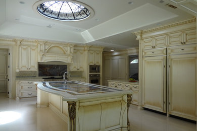 Eat-in kitchen - traditional u-shaped eat-in kitchen idea in Los Angeles with an integrated sink, raised-panel cabinets, light wood cabinets, marble countertops, white backsplash and paneled appliances