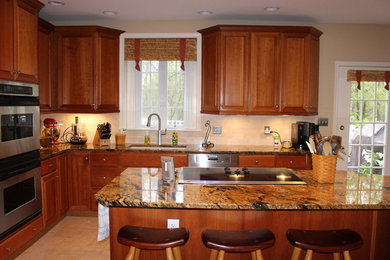 Kitchen - mid-sized traditional l-shaped travertine floor and beige floor kitchen idea in Philadelphia with an undermount sink, raised-panel cabinets, medium tone wood cabinets, granite countertops, white backsplash, subway tile backsplash, stainless steel appliances and an island