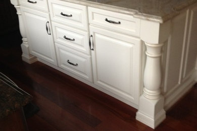 Diseño de cocina clásica de tamaño medio con armarios con paneles con relieve, puertas de armario blancas, encimera de cuarcita, suelo de madera oscura y una isla