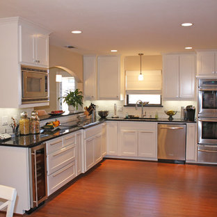 Elegant l-shaped kitchen photo in Dallas with stainless steel appliances, recessed-panel cabinets and white cabinets
