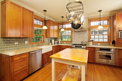 Eat-in kitchen - mid-sized traditional l-shaped medium tone wood floor eat-in kitchen idea in Chicago with a farmhouse sink, shaker cabinets, medium tone wood cabinets, granite countertops, green backsplash, glass tile backsplash, stainless steel appliances and an island