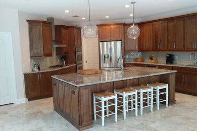 Large transitional u-shaped porcelain tile and beige floor kitchen photo in Miami with shaker cabinets, medium tone wood cabinets, granite countertops, gray backsplash, stainless steel appliances, an island, an undermount sink, subway tile backsplash and gray countertops
