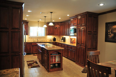 Example of a mid-sized classic u-shaped ceramic tile eat-in kitchen design in Dallas with a double-bowl sink, raised-panel cabinets, dark wood cabinets, granite countertops, beige backsplash, stone tile backsplash, stainless steel appliances and an island