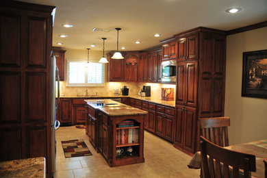 Photo of a medium sized classic u-shaped kitchen/diner in Dallas with a double-bowl sink, raised-panel cabinets, dark wood cabinets, granite worktops, beige splashback, stone tiled splashback, stainless steel appliances, ceramic flooring and an island.