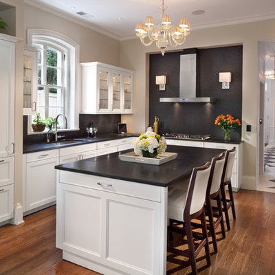Mid-sized elegant l-shaped medium tone wood floor eat-in kitchen photo in DC Metro with recessed-panel cabinets, white cabinets, black backsplash, paneled appliances, stone slab backsplash, an undermount sink, limestone countertops and an island