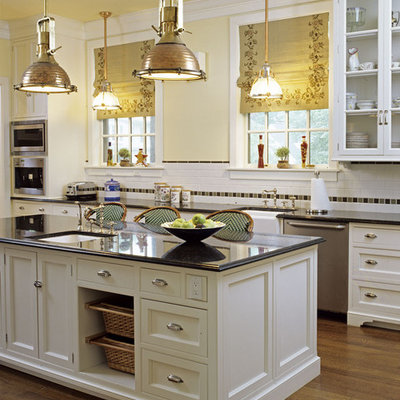 Mid-sized elegant u-shaped medium tone wood floor enclosed kitchen photo in Santa Barbara with stainless steel appliances, a farmhouse sink, granite countertops, recessed-panel cabinets, white backsplash, subway tile backsplash and an island