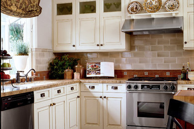 Small elegant l-shaped terra-cotta tile eat-in kitchen photo in San Diego with an undermount sink, raised-panel cabinets, white cabinets, wood countertops, green backsplash, subway tile backsplash, stainless steel appliances and an island