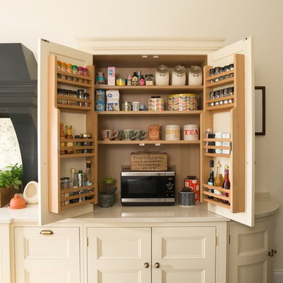 Example of a mid-sized classic dark wood floor kitchen pantry design in Kent with recessed-panel cabinets, quartzite countertops, mirror backsplash and black appliances