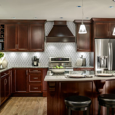 Inspiration for a mid-sized timeless l-shaped light wood floor and brown floor enclosed kitchen remodel in Vancouver with stainless steel appliances, a double-bowl sink, shaker cabinets, dark wood cabinets, granite countertops, gray backsplash, ceramic backsplash and an island