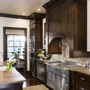 This is an example of a traditional kitchen in Charleston with glass-front cabinets, stainless steel appliances, limestone benchtops, dark wood cabinets, white splashback and subway tile splashback.