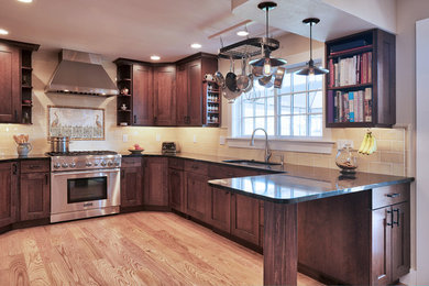 Example of a large classic u-shaped light wood floor and beige floor enclosed kitchen design in Other with an undermount sink, shaker cabinets, dark wood cabinets, granite countertops, beige backsplash, ceramic backsplash, stainless steel appliances, a peninsula and black countertops