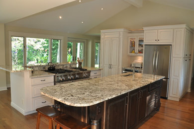 Example of a large classic dark wood floor kitchen pantry design in Grand Rapids with an undermount sink, recessed-panel cabinets, granite countertops, stainless steel appliances and two islands