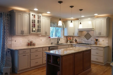 Example of a large classic u-shaped medium tone wood floor and brown floor open concept kitchen design in Denver with an undermount sink, raised-panel cabinets, white cabinets, granite countertops, beige backsplash, travertine backsplash, stainless steel appliances and an island