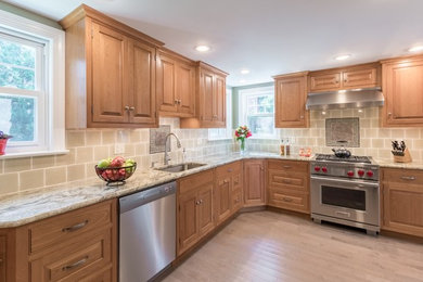 Example of a large classic light wood floor and beige floor enclosed kitchen design in Philadelphia with no island, an undermount sink, raised-panel cabinets, light wood cabinets, granite countertops, brown backsplash, ceramic backsplash and stainless steel appliances