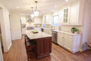 Eat-in kitchen - large traditional u-shaped medium tone wood floor and brown floor eat-in kitchen idea in New York with an undermount sink, shaker cabinets, white cabinets, quartzite countertops, white backsplash, porcelain backsplash, stainless steel appliances, an island and white countertops