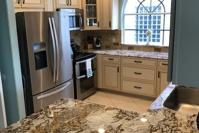 Mid-sized elegant u-shaped eat-in kitchen photo in Tampa with granite countertops and travertine backsplash