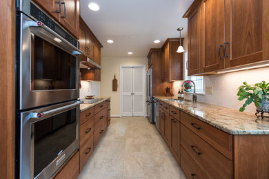 Example of a mid-sized classic galley beige floor and ceramic tile enclosed kitchen design in DC Metro with an undermount sink, shaker cabinets, medium tone wood cabinets, granite countertops, white backsplash, subway tile backsplash, stainless steel appliances and no island
