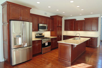 Example of a mid-sized classic l-shaped dark wood floor and brown floor open concept kitchen design in New York with an undermount sink, raised-panel cabinets, dark wood cabinets, quartz countertops, stainless steel appliances and an island