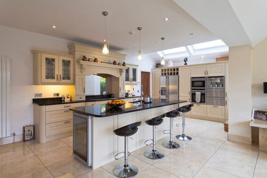 Inspiration for a large classic single-wall open plan kitchen in Dublin with a double-bowl sink, raised-panel cabinets, white cabinets, quartz worktops, stainless steel appliances, porcelain flooring and an island.