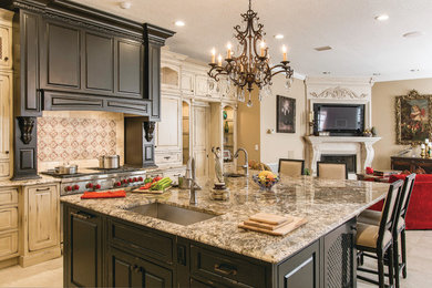 Large elegant l-shaped open concept kitchen photo in Tampa with raised-panel cabinets, distressed cabinets, granite countertops, an undermount sink, beige backsplash, travertine backsplash, stainless steel appliances and an island