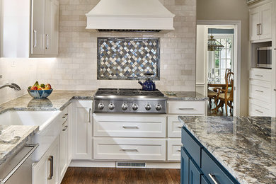 Eat-in kitchen - mid-sized traditional medium tone wood floor and brown floor eat-in kitchen idea in Dallas with a farmhouse sink, recessed-panel cabinets, white cabinets, granite countertops, beige backsplash, stainless steel appliances, an island and multicolored countertops