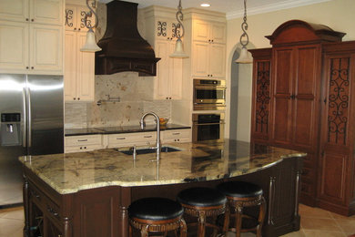 Eat-in kitchen - mid-sized traditional l-shaped porcelain tile eat-in kitchen idea in Orlando with an undermount sink, raised-panel cabinets, white cabinets, granite countertops, beige backsplash, stone tile backsplash, stainless steel appliances and an island