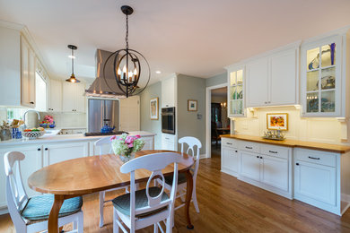 Eat-in kitchen - large country l-shaped dark wood floor and brown floor eat-in kitchen idea in Milwaukee with an undermount sink, recessed-panel cabinets, white cabinets, quartzite countertops, white backsplash, ceramic backsplash, stainless steel appliances and a peninsula