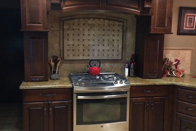 Inspiration for a large timeless u-shaped travertine floor eat-in kitchen remodel in Wichita with a farmhouse sink, raised-panel cabinets, dark wood cabinets, granite countertops, beige backsplash, stone tile backsplash, stainless steel appliances and a peninsula