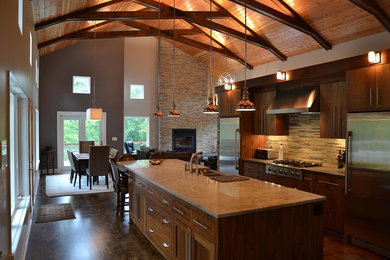 Example of a large mountain style single-wall dark wood floor and brown floor open concept kitchen design in Orange County with a farmhouse sink, flat-panel cabinets, medium tone wood cabinets, quartz countertops, stainless steel appliances, an island, multicolored backsplash and stone tile backsplash