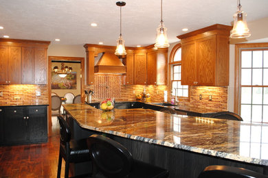 Example of a mid-sized transitional u-shaped medium tone wood floor and brown floor eat-in kitchen design in Cleveland with a single-bowl sink, shaker cabinets, brown cabinets, granite countertops, brown backsplash, glass tile backsplash, stainless steel appliances and an island