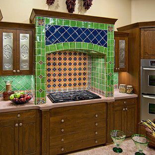 Large mediterranean u-shaped open plan kitchen in Albuquerque with a single-bowl sink, raised-panel cabinets, distressed cabinets, solid surface benchtops, multi-coloured splashback, terra-cotta splashback, stainless steel appliances, ceramic floors and with island.