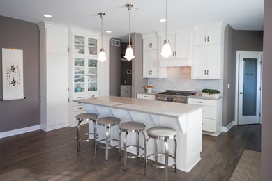 Inspiration for a mid-sized timeless l-shaped dark wood floor and brown floor eat-in kitchen remodel in Grand Rapids with white cabinets, an island, beige countertops, shaker cabinets, quartz countertops, subway tile backsplash, stainless steel appliances, multicolored backsplash and a drop-in sink