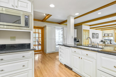 Example of a classic kitchen design in Milwaukee with raised-panel cabinets, white cabinets and black countertops