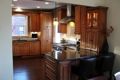 Inspiration for a small timeless l-shaped dark wood floor enclosed kitchen remodel in Detroit with a double-bowl sink, raised-panel cabinets, medium tone wood cabinets, solid surface countertops, white backsplash, stone tile backsplash, stainless steel appliances and a peninsula