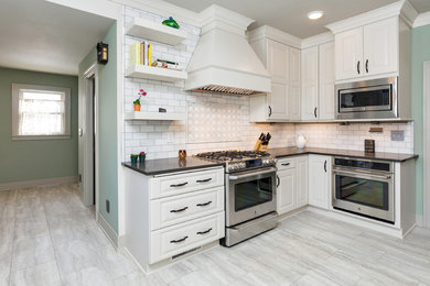 Elegant l-shaped gray floor eat-in kitchen photo in Other with a farmhouse sink, raised-panel cabinets, white cabinets, quartz countertops, white backsplash, marble backsplash, stainless steel appliances and no island