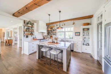 Eat-in kitchen - large traditional l-shaped medium tone wood floor and brown floor eat-in kitchen idea with a farmhouse sink, flat-panel cabinets, white cabinets, quartz countertops, beige backsplash, stainless steel appliances, an island and white countertops