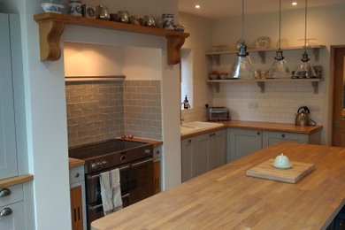Inspiration for a medium sized classic l-shaped open plan kitchen in Cambridgeshire with shaker cabinets, grey cabinets, wood worktops, white splashback, metro tiled splashback and an island.