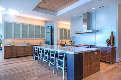 This is an example of a large modern galley kitchen/diner in Phoenix with a submerged sink, flat-panel cabinets, medium wood cabinets, granite worktops, stainless steel appliances, light hardwood flooring, an island and metallic splashback.