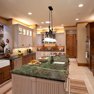 Large traditional galley eat-in kitchen in Houston with a farmhouse sink, raised-panel cabinets, granite benchtops, stainless steel appliances, brown cabinets, beige splashback, with island, beige floor and green benchtop.