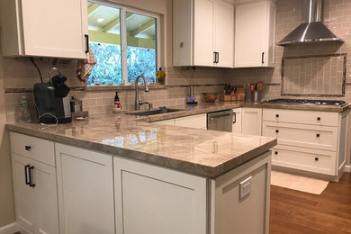 Inspiration for a mid-sized timeless u-shaped light wood floor and brown floor eat-in kitchen remodel in San Francisco with flat-panel cabinets, no island, an undermount sink, beige cabinets, quartz countertops, beige backsplash, porcelain backsplash, stainless steel appliances and beige countertops