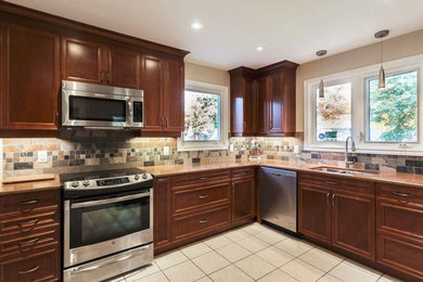 Kitchen - mid-sized traditional l-shaped kitchen idea in Ottawa with an undermount sink, shaker cabinets, medium tone wood cabinets, quartz countertops, multicolored backsplash, stone tile backsplash, stainless steel appliances and no island