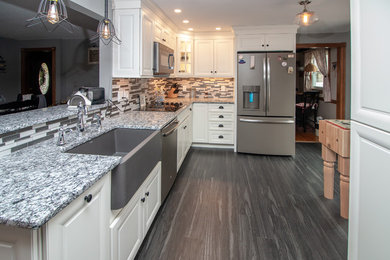 Example of a mid-sized classic galley vinyl floor and gray floor eat-in kitchen design in Manchester with a farmhouse sink, flat-panel cabinets, white cabinets, granite countertops, gray backsplash, glass sheet backsplash, stainless steel appliances, no island and multicolored countertops