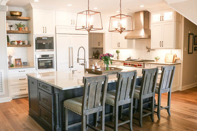 Kitchen - large traditional l-shaped light wood floor kitchen idea in Austin with a farmhouse sink, shaker cabinets, white cabinets, white backsplash, ceramic backsplash, stainless steel appliances and an island