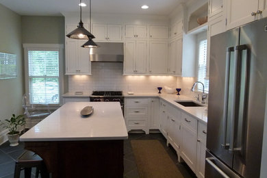 Mid-sized elegant l-shaped porcelain tile eat-in kitchen photo in New York with an undermount sink, shaker cabinets, white cabinets, quartz countertops, white backsplash, ceramic backsplash, stainless steel appliances and an island