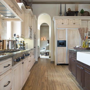 Idee per una grande cucina tradizionale chiusa con lavello stile country, ante con bugna sagomata, ante con finitura invecchiata, top in granito, paraspruzzi marrone, paraspruzzi in travertino, elettrodomestici da incasso, pavimento in legno massello medio e pavimento marrone