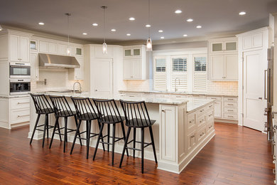 Inspiration for a large transitional u-shaped medium tone wood floor open concept kitchen remodel in Columbus with shaker cabinets, white cabinets, marble countertops, white backsplash, subway tile backsplash, stainless steel appliances, an island and a triple-bowl sink