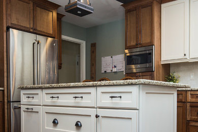 Example of a mid-sized classic galley eat-in kitchen design in Detroit with a farmhouse sink, flat-panel cabinets, brown cabinets, granite countertops, white backsplash, subway tile backsplash, stainless steel appliances and an island